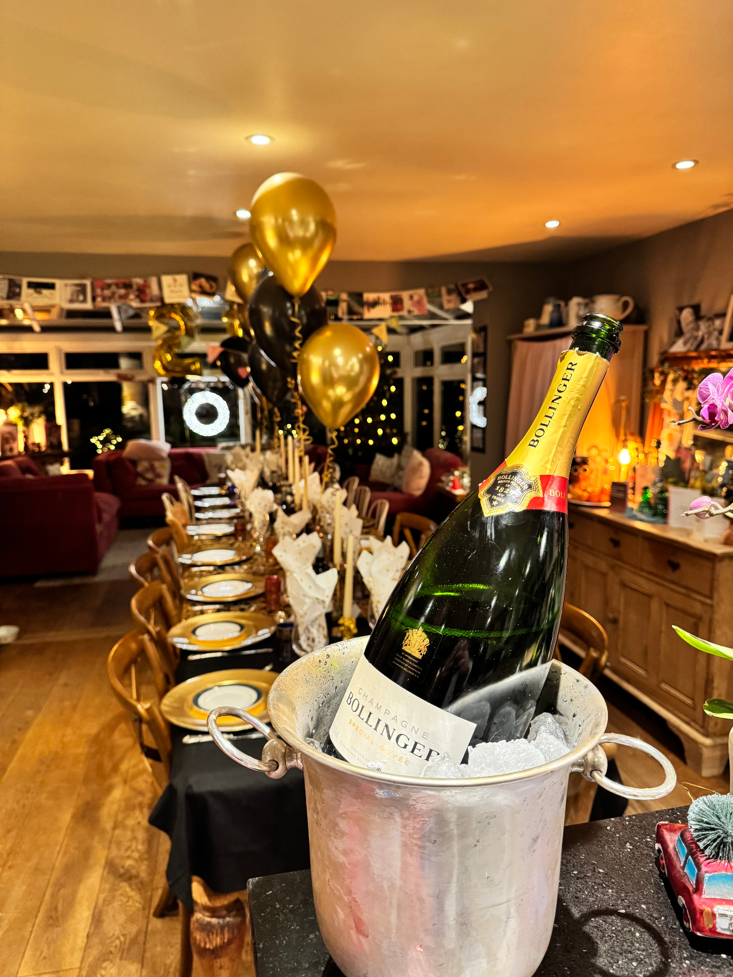 Magnum of Bollinger champagne chilling beside a gold and black birthday table setting